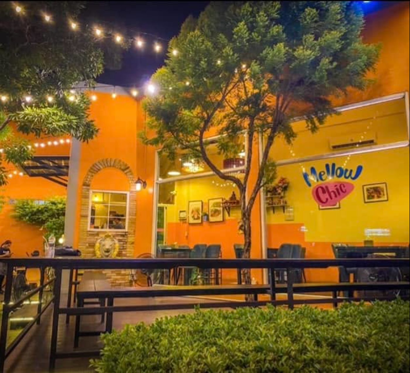 Mellow Chic at night, orange facade under string lights